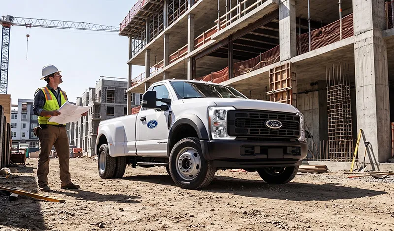 Construction site with a Ford pickup truck and a worker inspecting plans, representing the commercial vehicles available at MSA Ford in Abbotsford, BC.